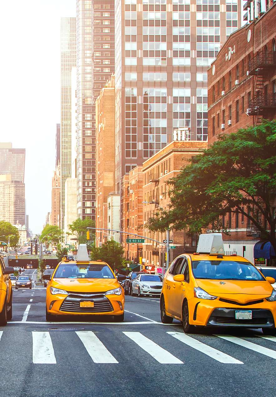 Vista de Times Square, con taxis amarillos, un autobús escolar y personas cruzando la calle