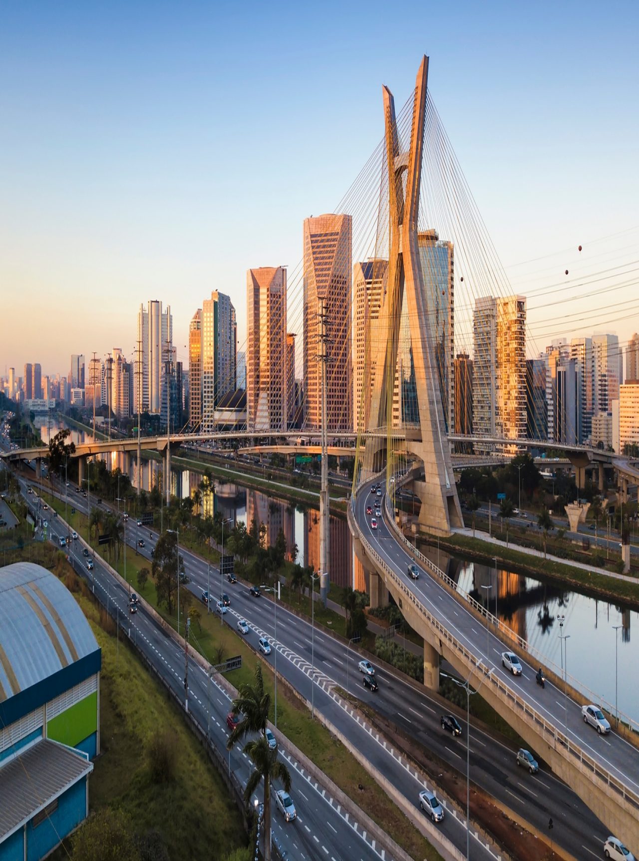 Paisaje urbano de São Paulo con el Puente Estaiada cruzando el Río Pinheiros bajo un cielo azul.