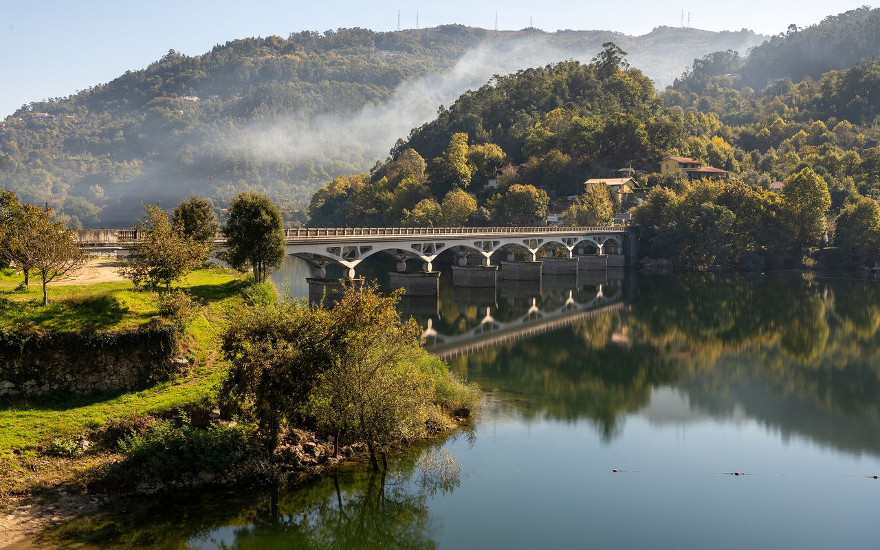 Paisaje del norte de Portugal con un puente de piedra sobre un río, rodeado de colinas verdes