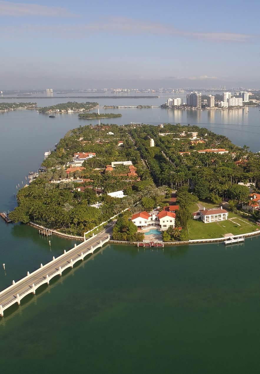 Vista aérea de Star Island em Miami, com casas luxuosas e uma intensa vegetação com uma ponte conectando a ilha à cidade