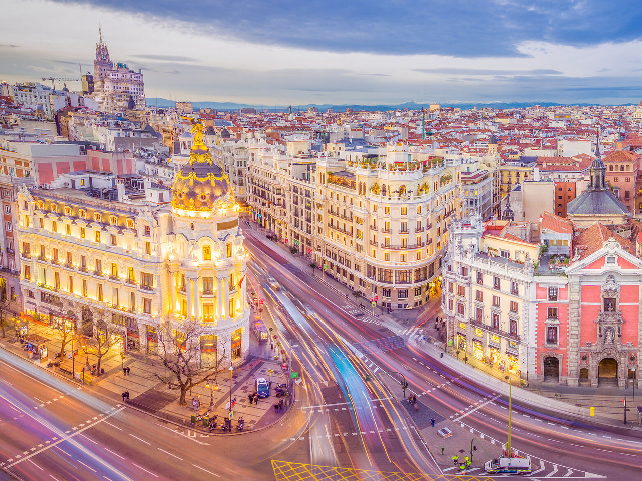 Vista aérea sobre a cidade de Madrid, ao pôr-do-sol, onde se vê o dinamismo das ruas muito movimentadas