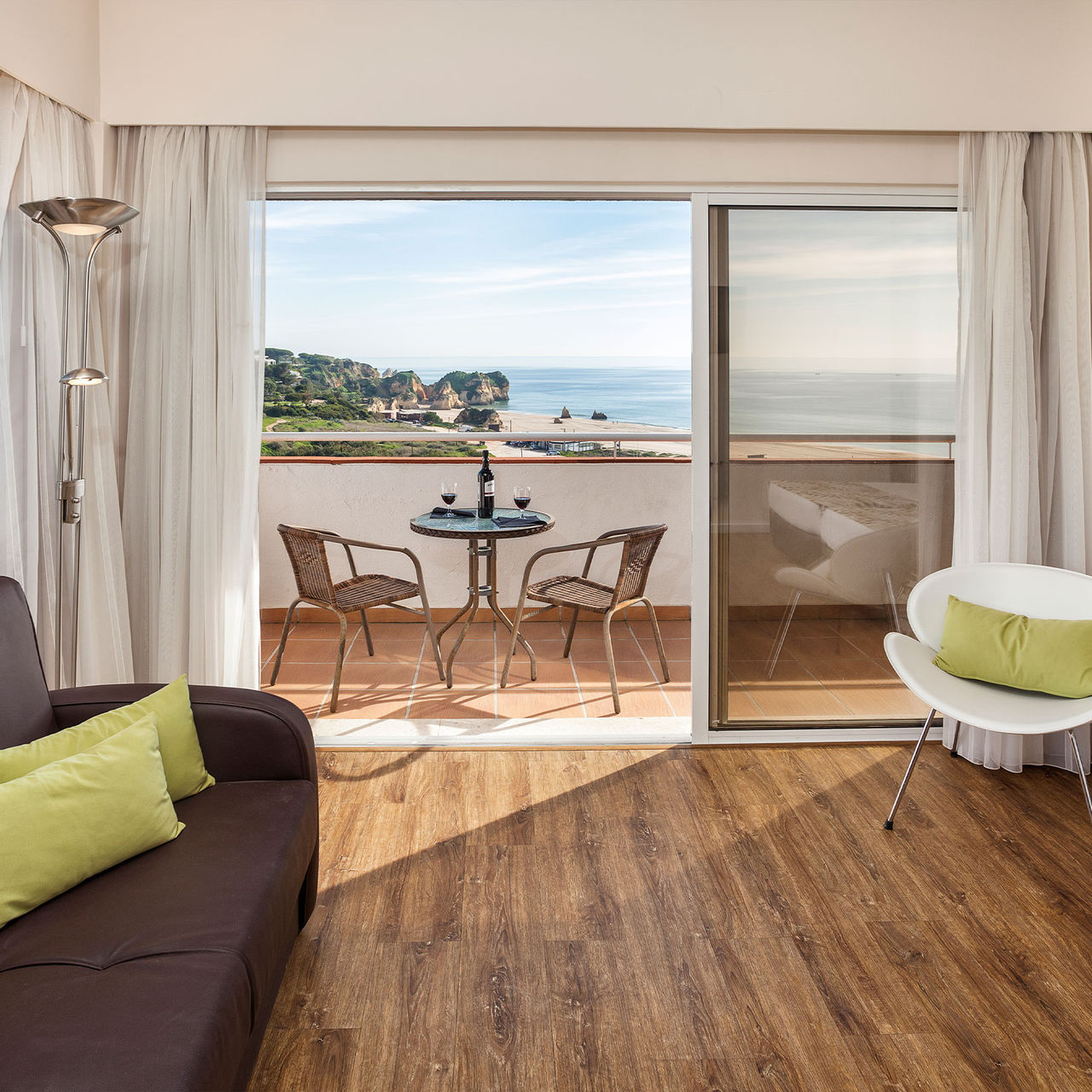 Vista de um apartamento no Pestana Alvor Atlântico, com uma varanda com vista mar e dois copos de vinho