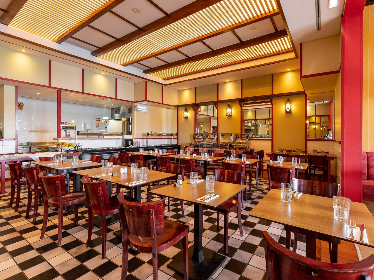 O restaurante Luigi, do Resort de 5 Estrelas no Porto Santo tem um chão com azulejos brancos e pretos e cadeiras escuras