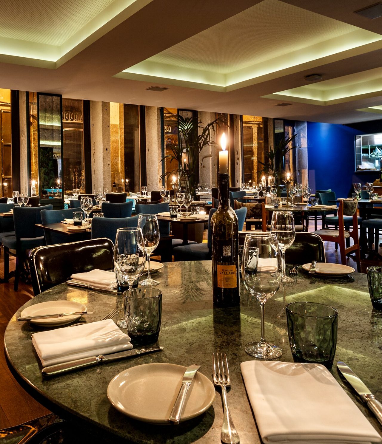 O restaurante Rib Beef & Wine, do Hotel 5 Estrelas no Centro do Porto, tem mesas redondas com loiça e vinho