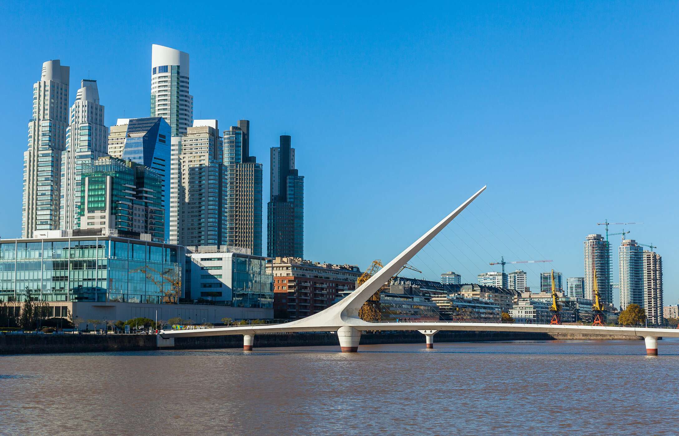 Die ikonische Puente de la Mujer, in Segelform, über einem Fluss in Buenos Aires, mit Puerto Madero im Hintergrund