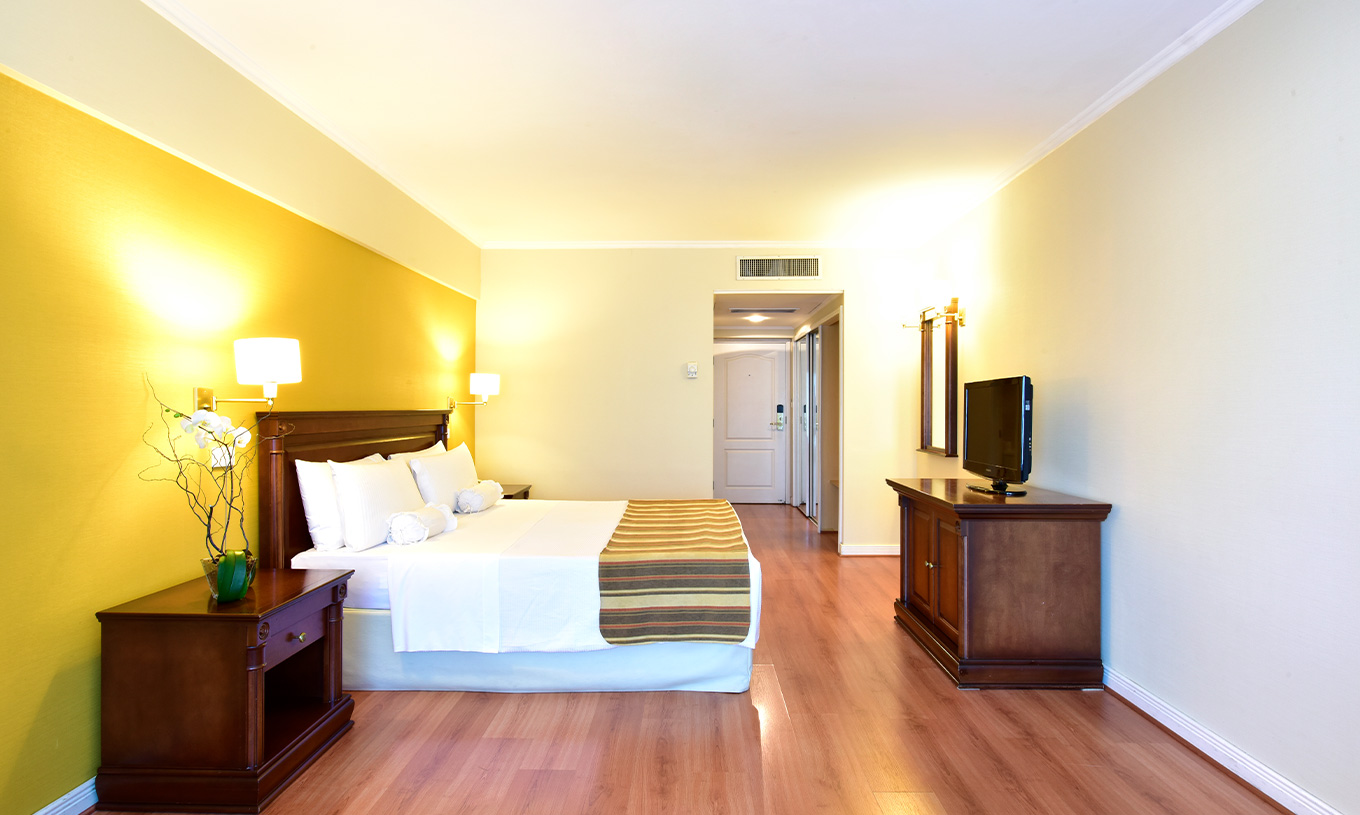 Das Queen Deluxe Zimmer im Pestana Buenos Aires hat ein Doppelbett, Fernseher, Spiegel und Nachttisch mit Lampe