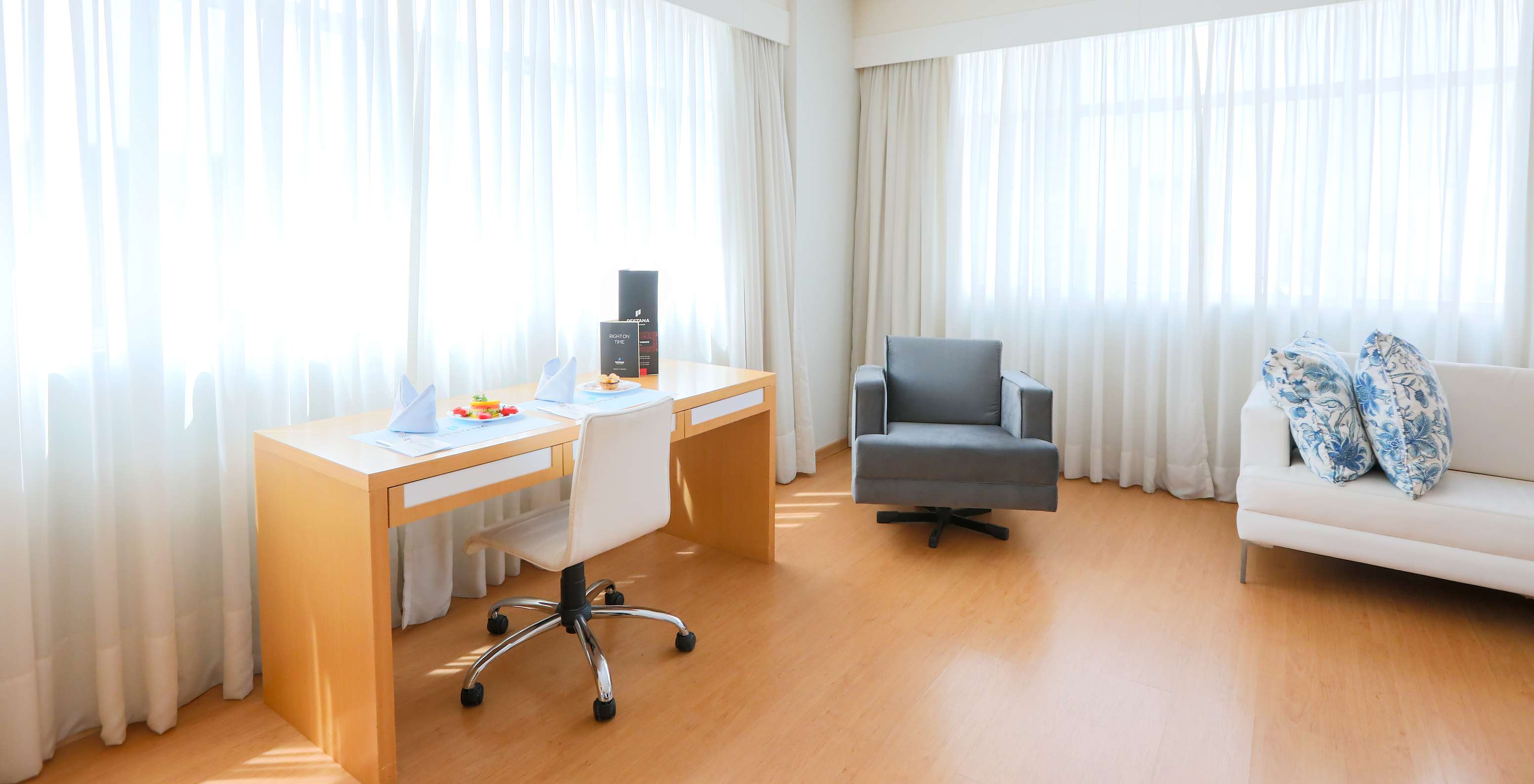 Der Deluxe-Eckzimmer im Pestana Curitiba hat Sofas und einen Schreibtisch neben zwei großen Fenstern mit viel Licht