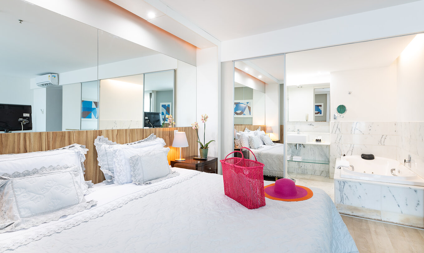 Die Junior Suite mit seitlichem Meerblick hat ein Doppelbett, einen Spiegel und ein Bad mit Whirlpool 