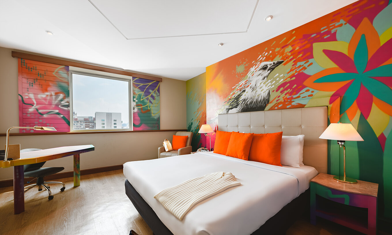 Das Art Room im Pestana São Paulo hat ein Doppelbett und bunte Gemälde an der Wand