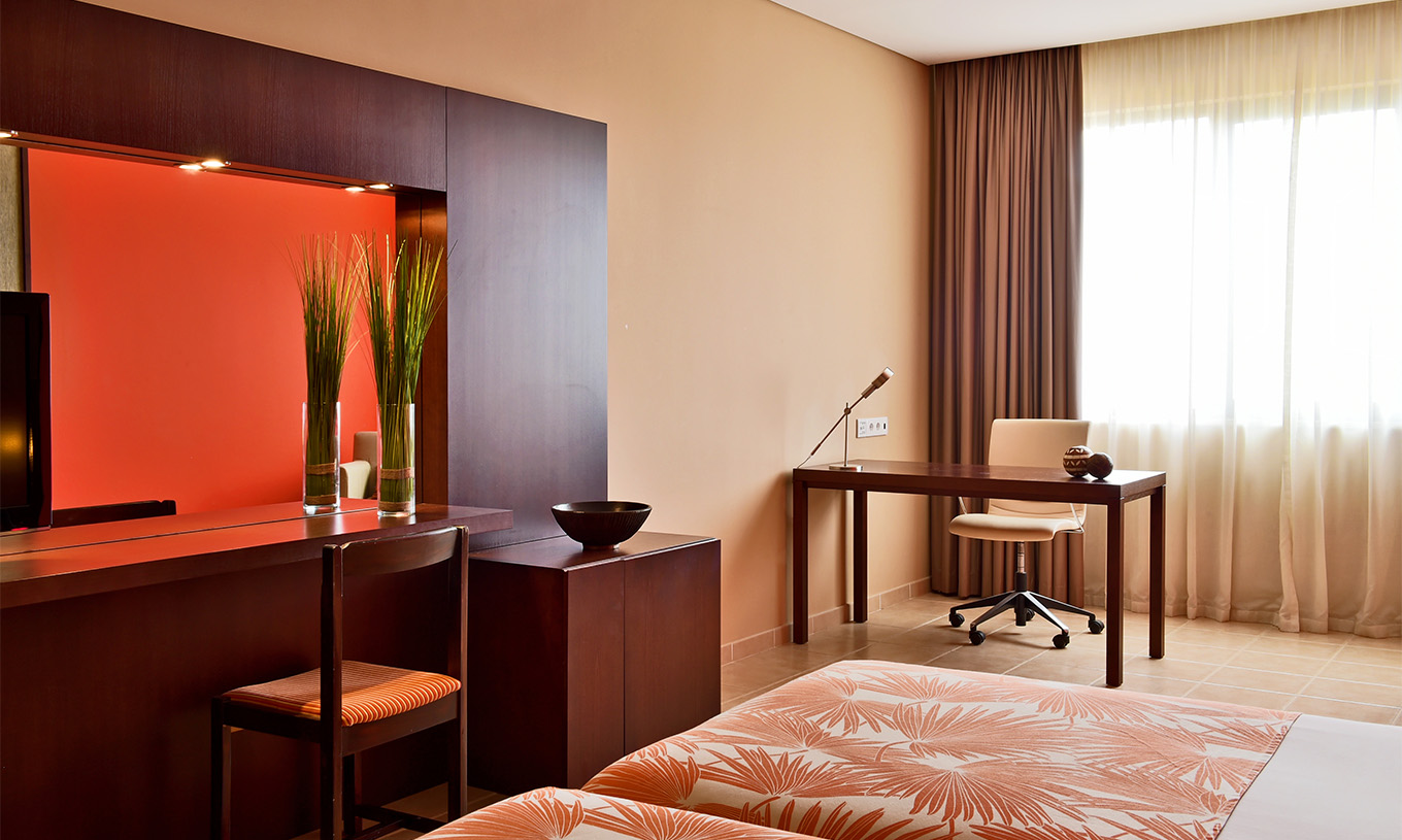 Classic Sea View Zimmer Pestana Tropico hat einen Schreibtisch mit Lampe, einen Stuhl, Bett und Spiegel