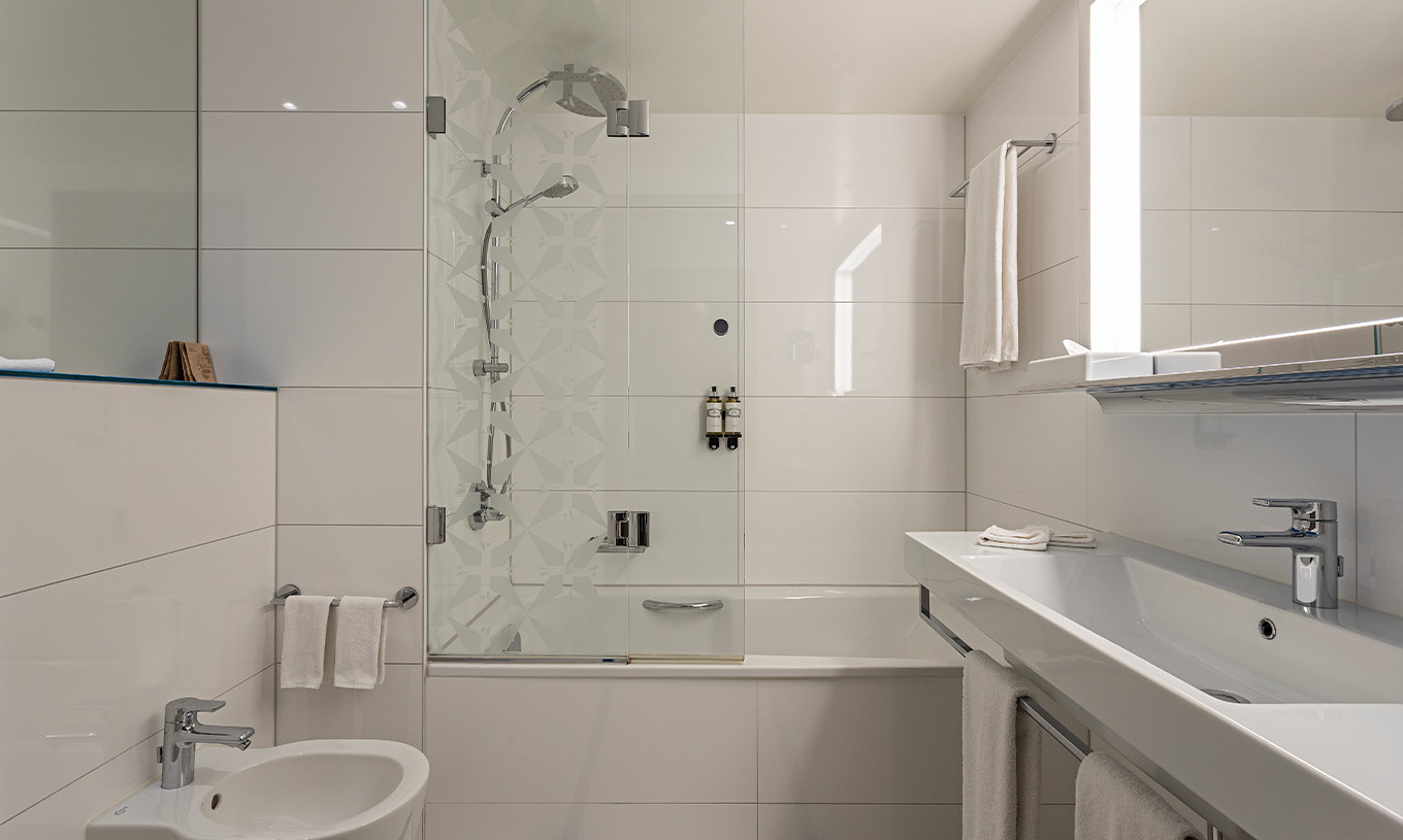 Das Grand Deluxe Zimmer im Pestana Berlin Tiergarten hat ein Bad mit Badewanne und Dusche und ein Waschbecken