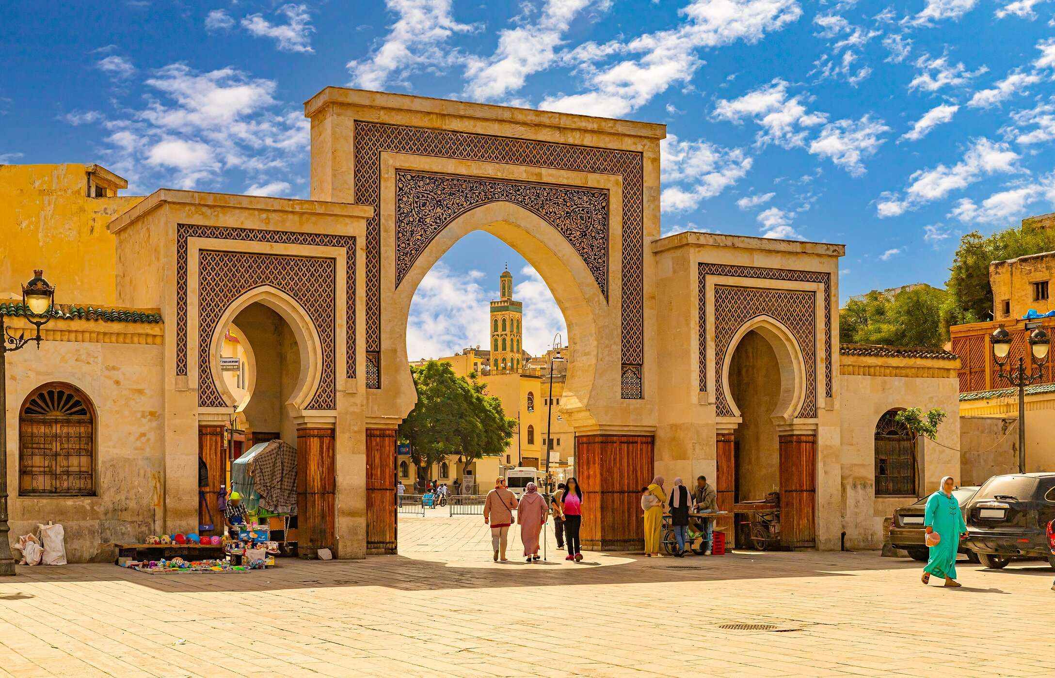 Typische marokkanische Bögen in Fès, mit sandfarbenen Fliesen und Menschen in traditioneller Kleidung.