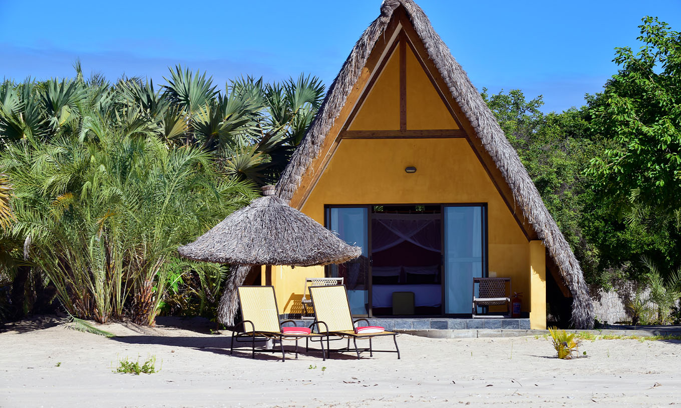 Der Bungalow T1 im Pestana Bazaruto Lodge ist ein gelbes Häuschen am Strand mit einem Strohdach in A-Form