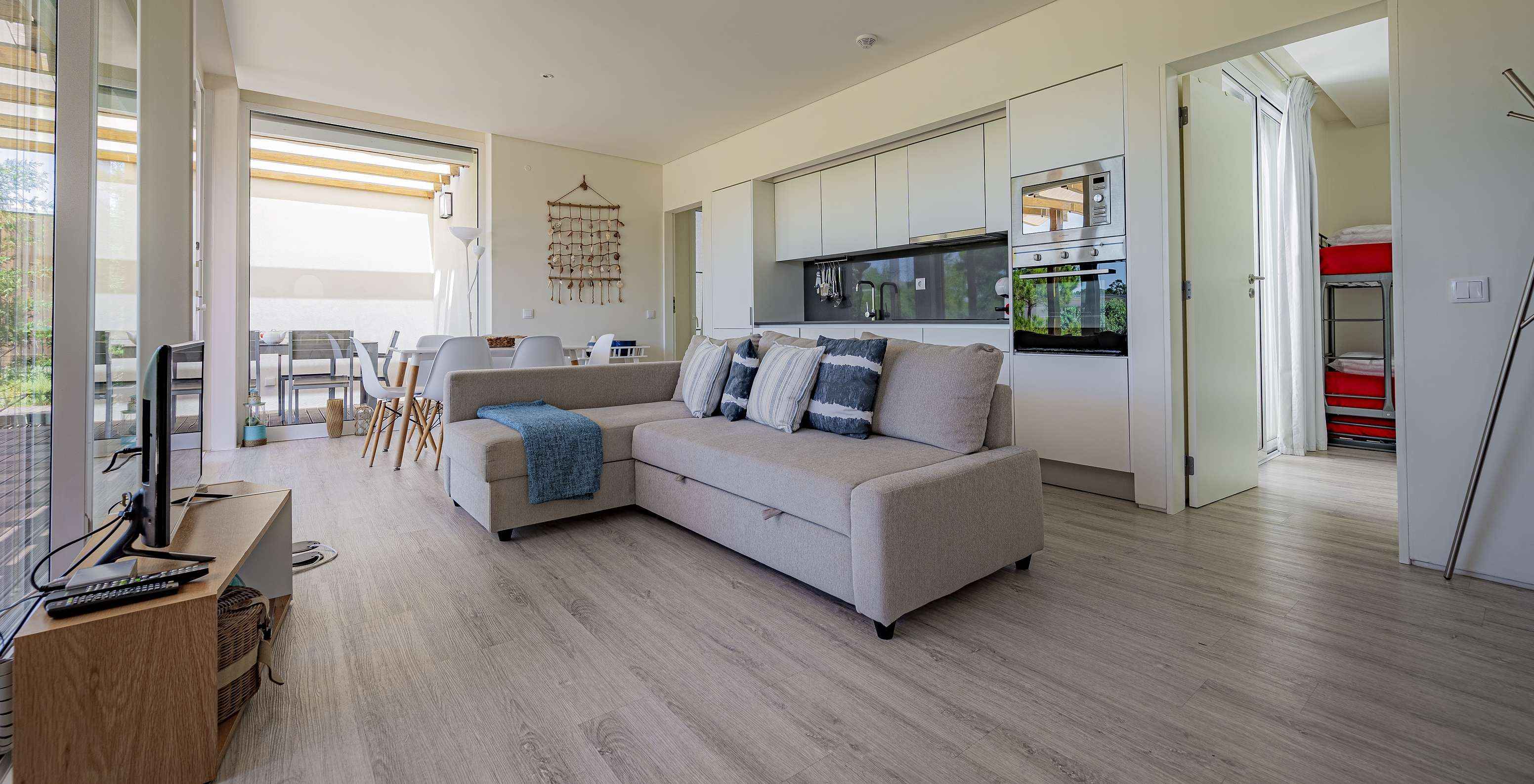 Die Green Villa im Pestana Tróia Eco Resort hat einen Wohnbereich mit Küche, Sofa, Essbereich und Fernseher