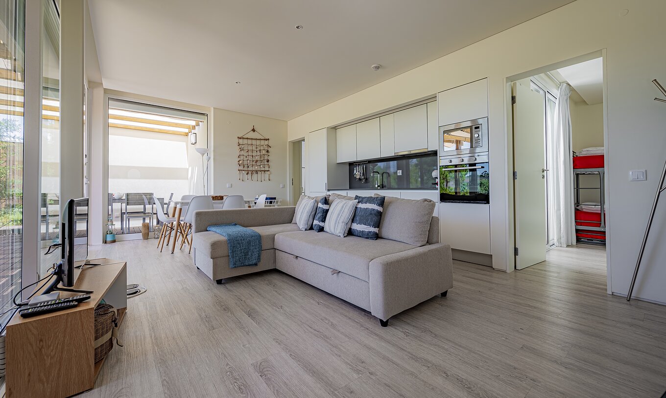 Die Green Villa im Pestana Tróia Eco Resort hat einen Wohnbereich mit Küche, Sofa, Essbereich und Fernseher
