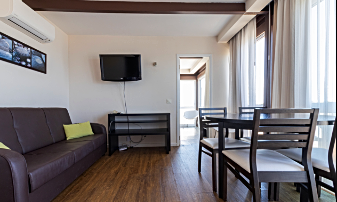 Das Superior Studio Sea View im Pestana Alvor Atlântico verfügt über einen hellen Wohnbereich mit Sofa, Esstisch und Fernseher und bietet eine gemütliche Atmosphäre mit großen Fenstern, die viel natürliches Licht hereinlassen.