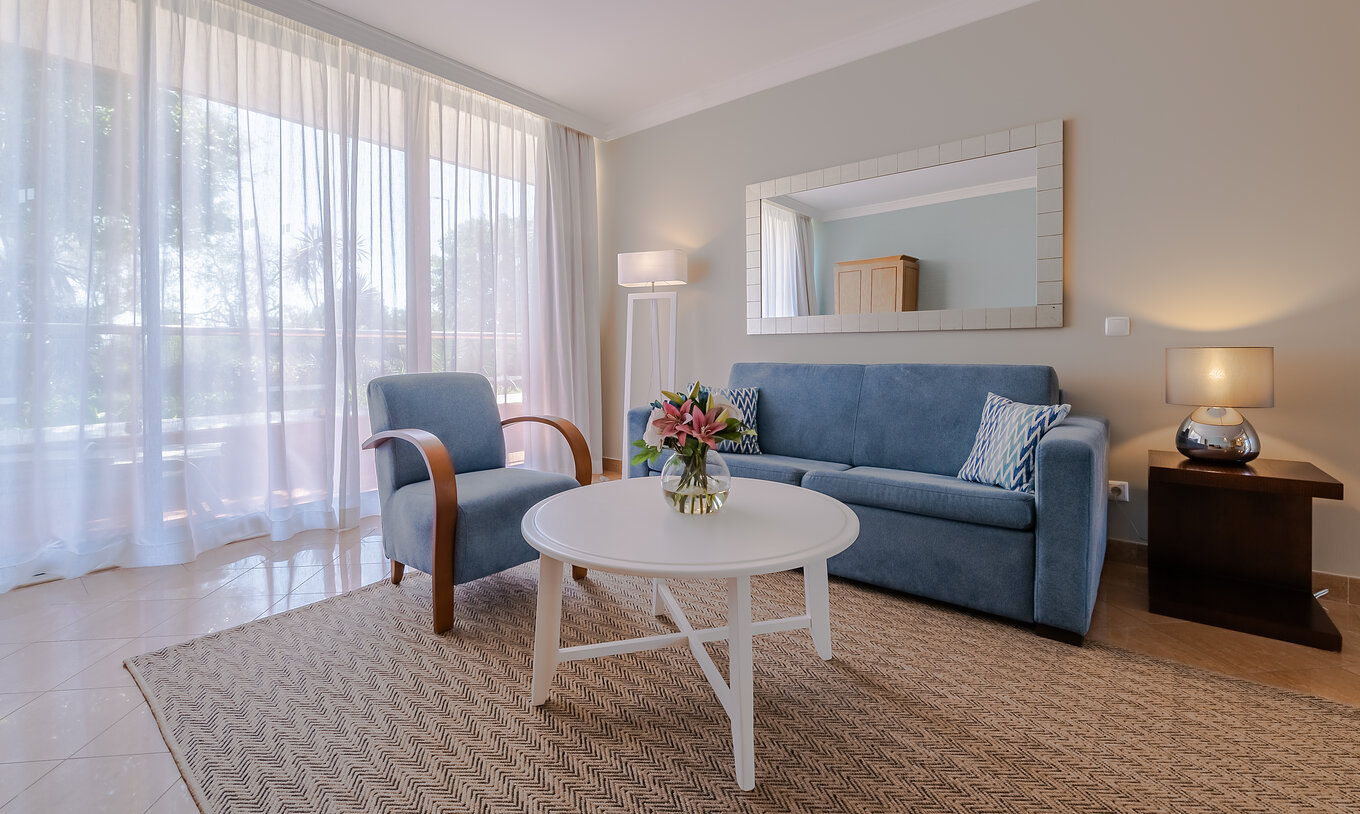 Das T1 - mit 1 Schlafzimmer im Pestana Alvor Park hat ein Wohnzimmer mit einem blauen Sofa und einem Sessel
