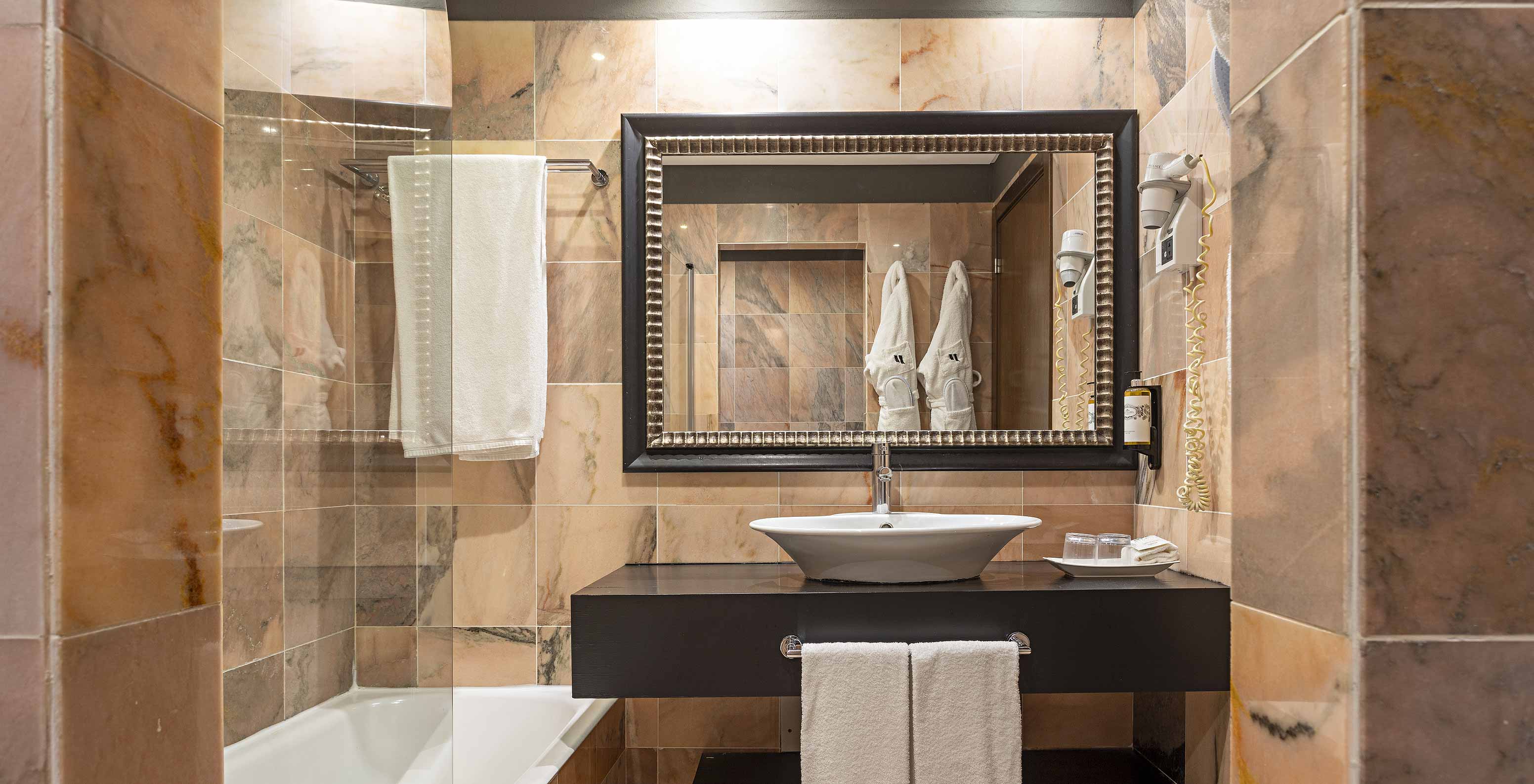 Die Cliff Suite T1 im Pestana Alvor Praia hat ein Badezimmer mit einer Badewanne, zwei Bademänteln und einem Haartrockner