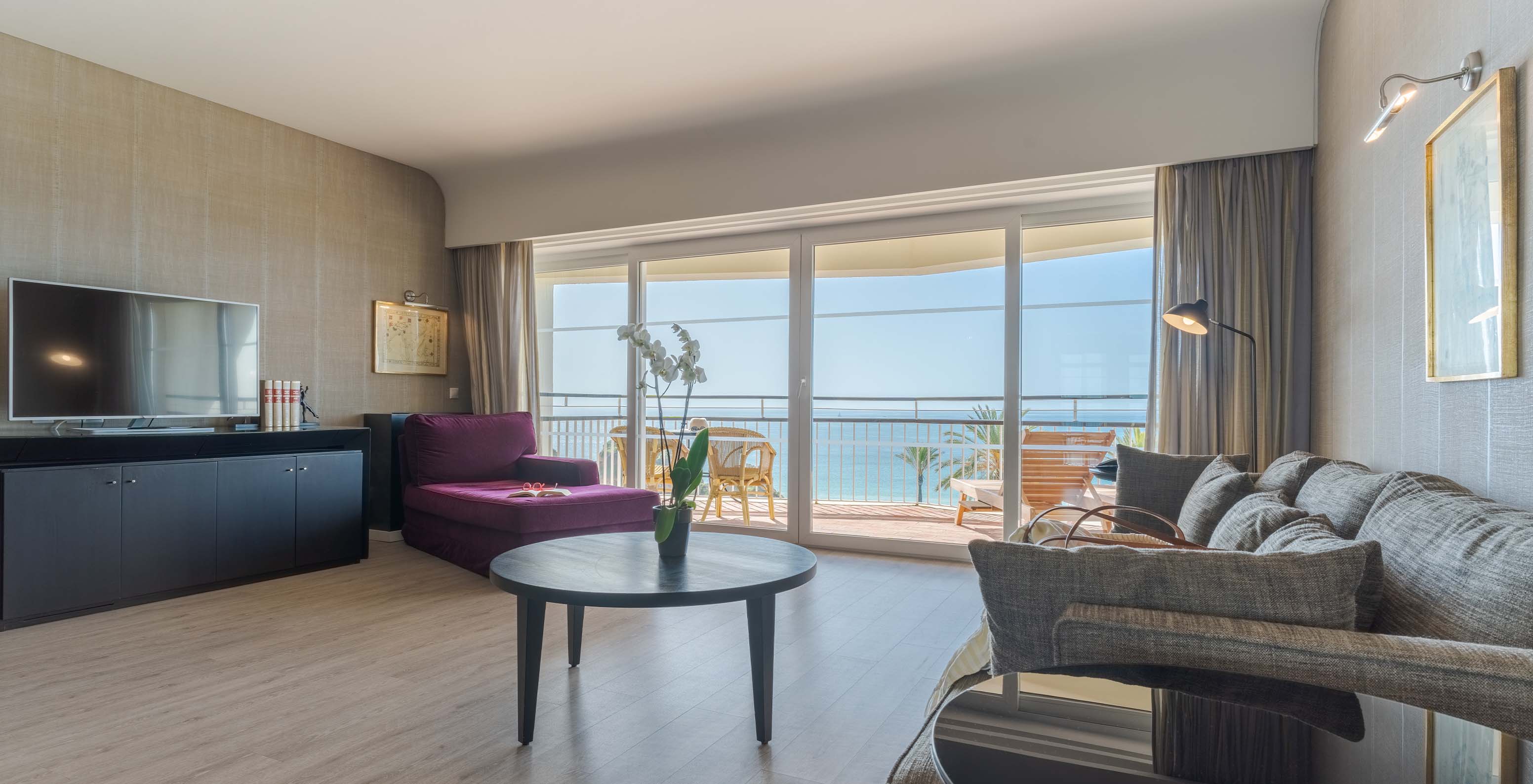 Die Luxussuite mit Meerblick im Pestana Alvor Praia hat ein Wohnzimmer mit Sofa, Sessel, Tisch, Fernseher und Balkon