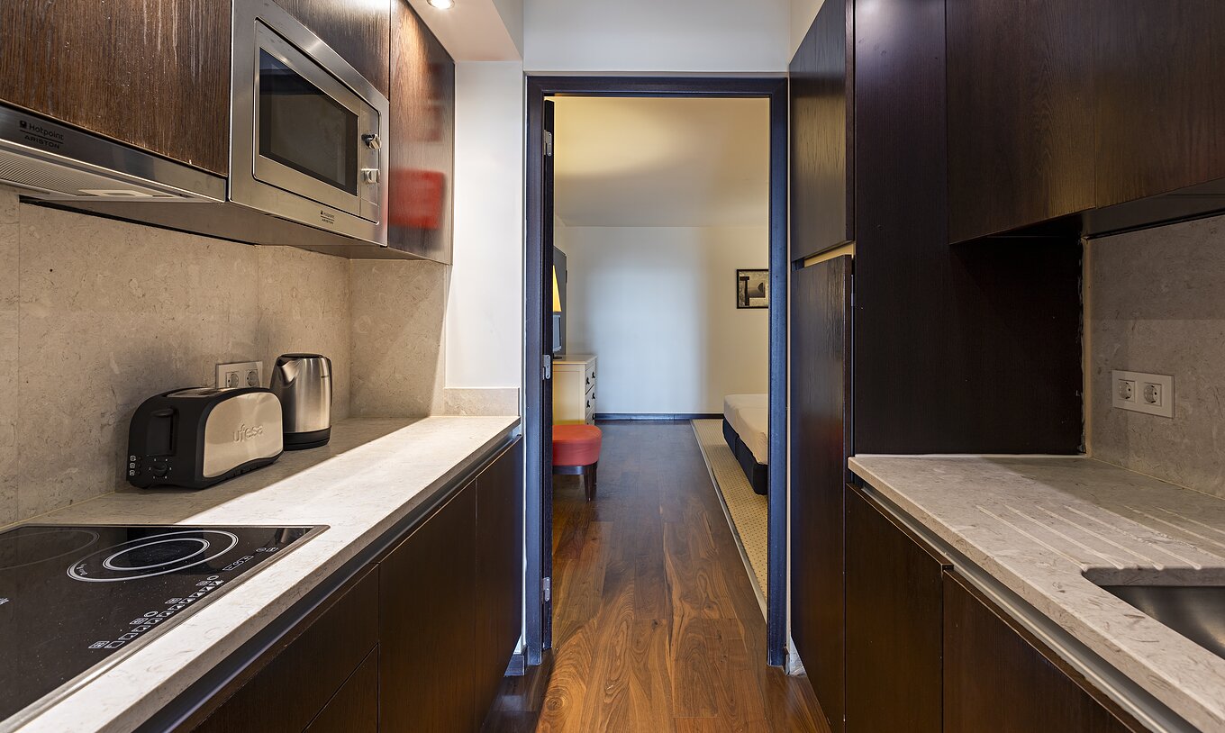 Die Cliff Suite T2 im Pestana Alvor Praia hat eine Küche aus dunklem Holz und Stein, mit Herd und Mikrowelle