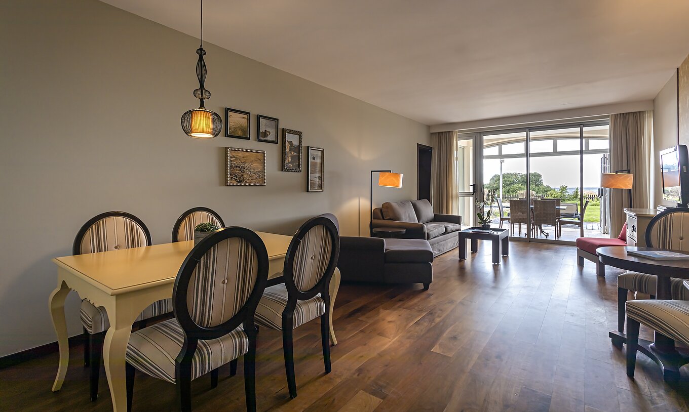 Die Cliff Suite T2 im Pestana Alvor Praia hat ein Wohnzimmer mit zwei Sofas, einem Fernseher, Esstisch und einer Veranda