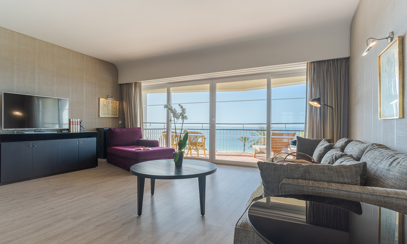 Die Luxussuite mit Meerblick im Pestana Alvor Praia hat ein Wohnzimmer mit Sofa, Sessel, Tisch, Fernseher und Balkon