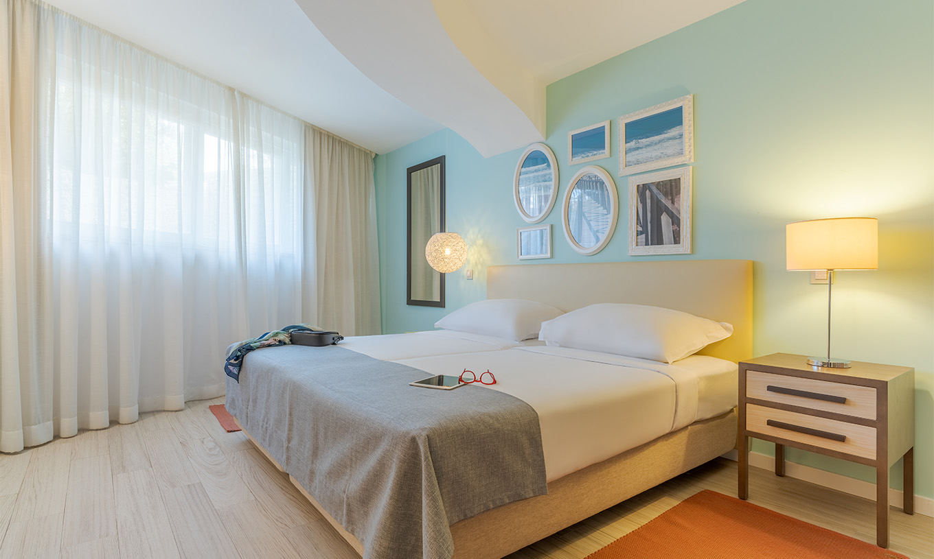 Die Suite T1 mit Gartenblick im Pestana Alvor Praia hat zwei Betten, Nachttisch mit Lampe, Teppich und Bilder