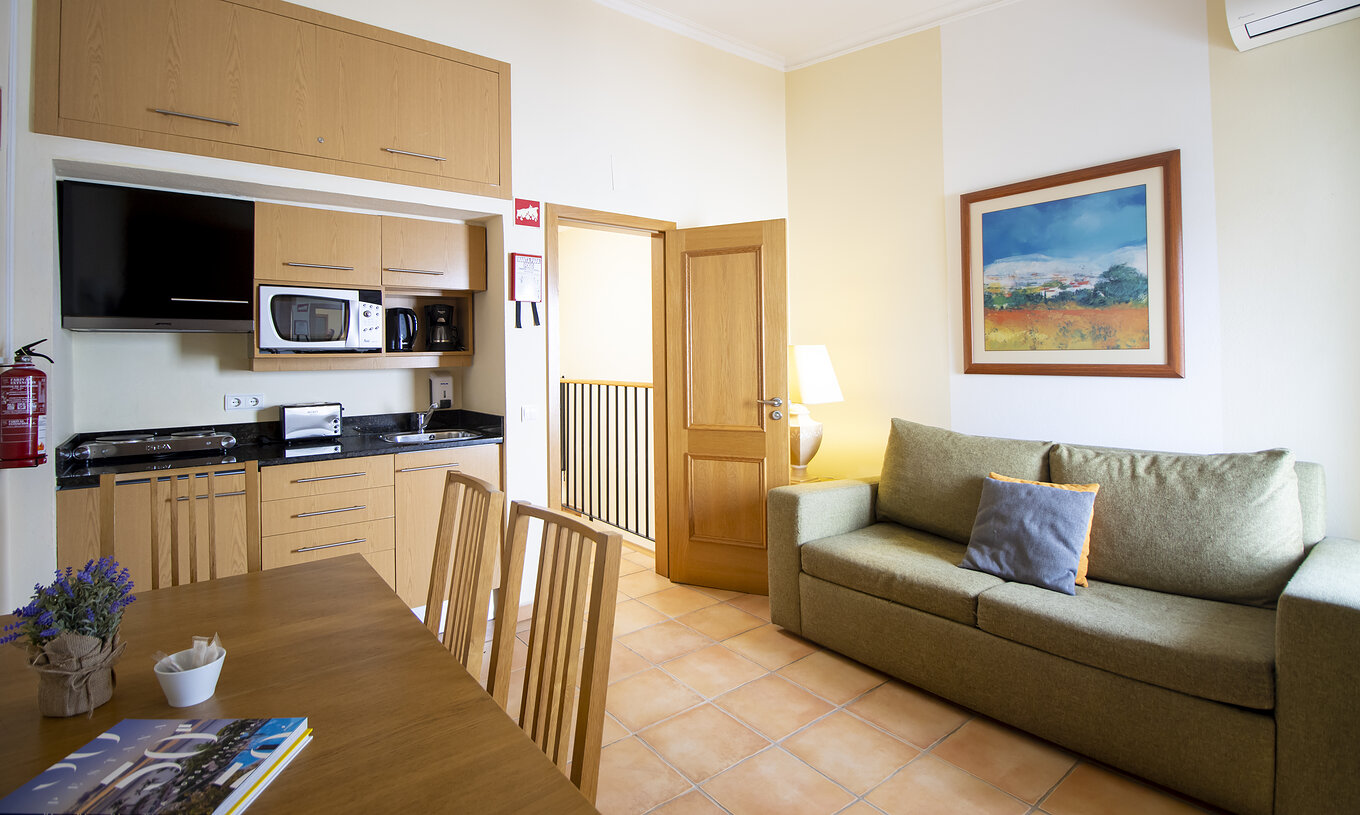 Das T1 Appartement - Terra im Pestana Palm Gardens hat ein Wohnzimmer mit Sofa, Tisch und Küchenzeile mit Mikrowelle