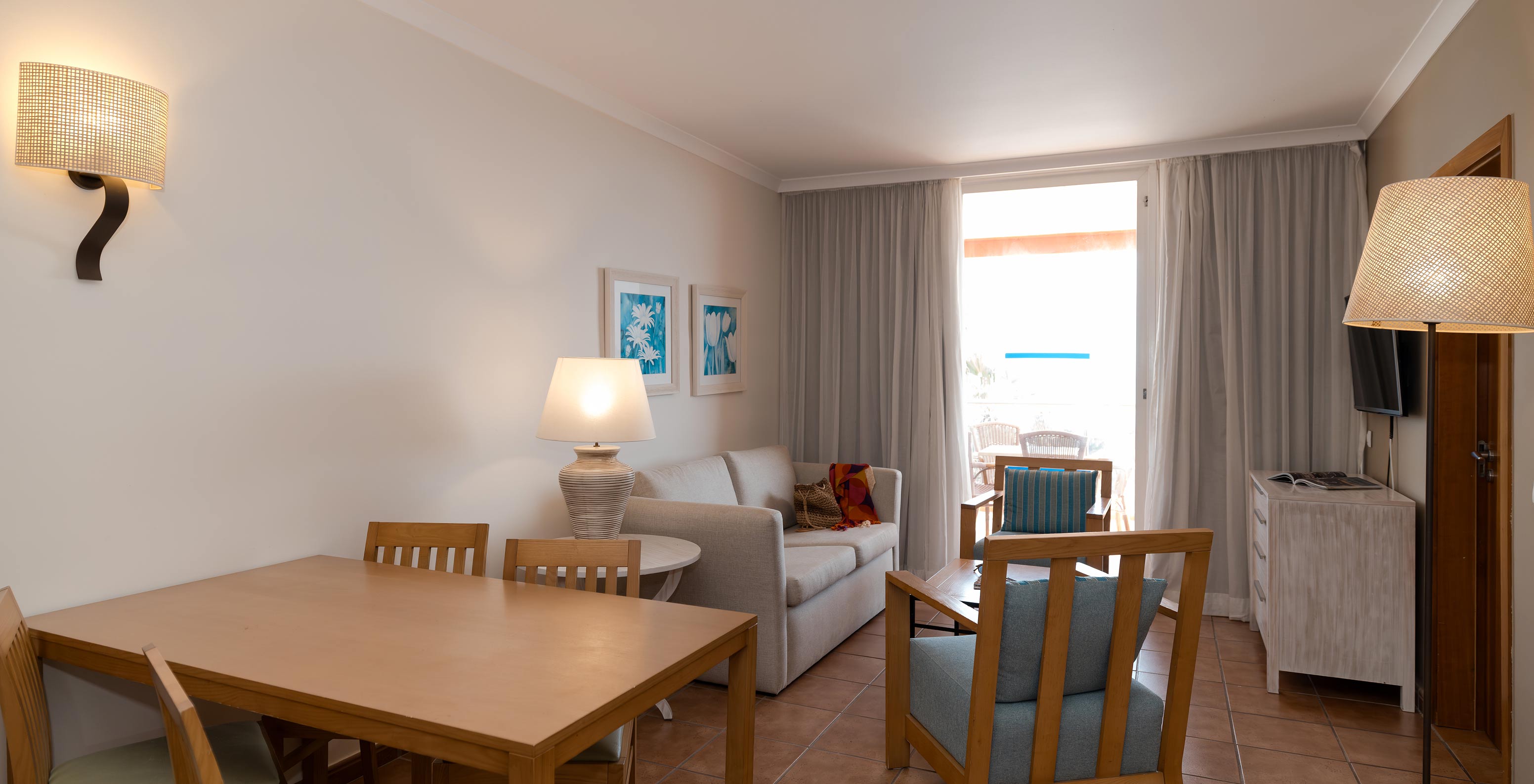 Die T2 Suite im Pestana Viking hat ein Wohnzimmer mit Sofa, zwei Sesseln und Fenster mit Zugang zum Balkon