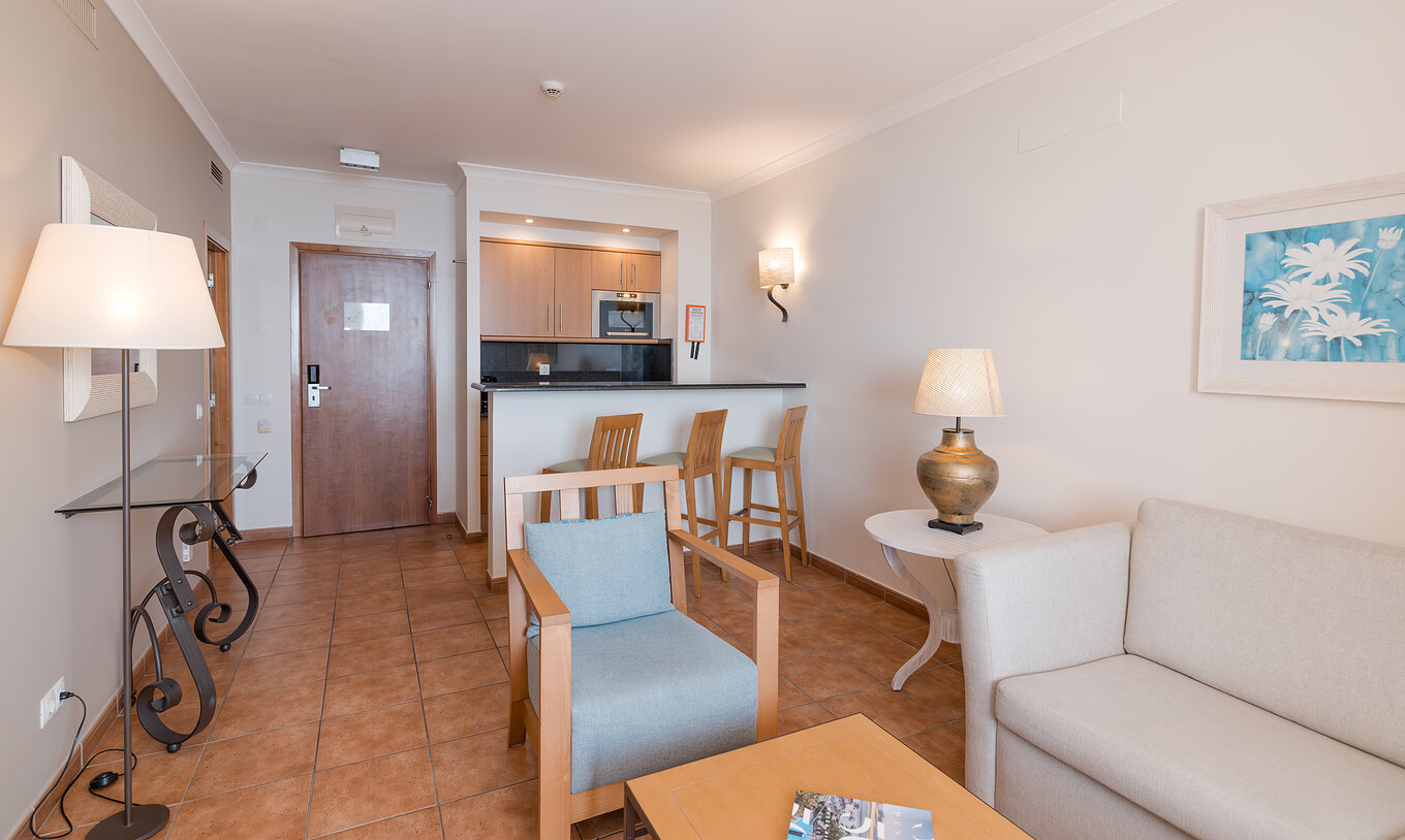 Die Suite Meerblick im Pestana Viking hat ein Wohnzimmer mit Sofa, Sesseln und kleine Küche mit Mikrowelle