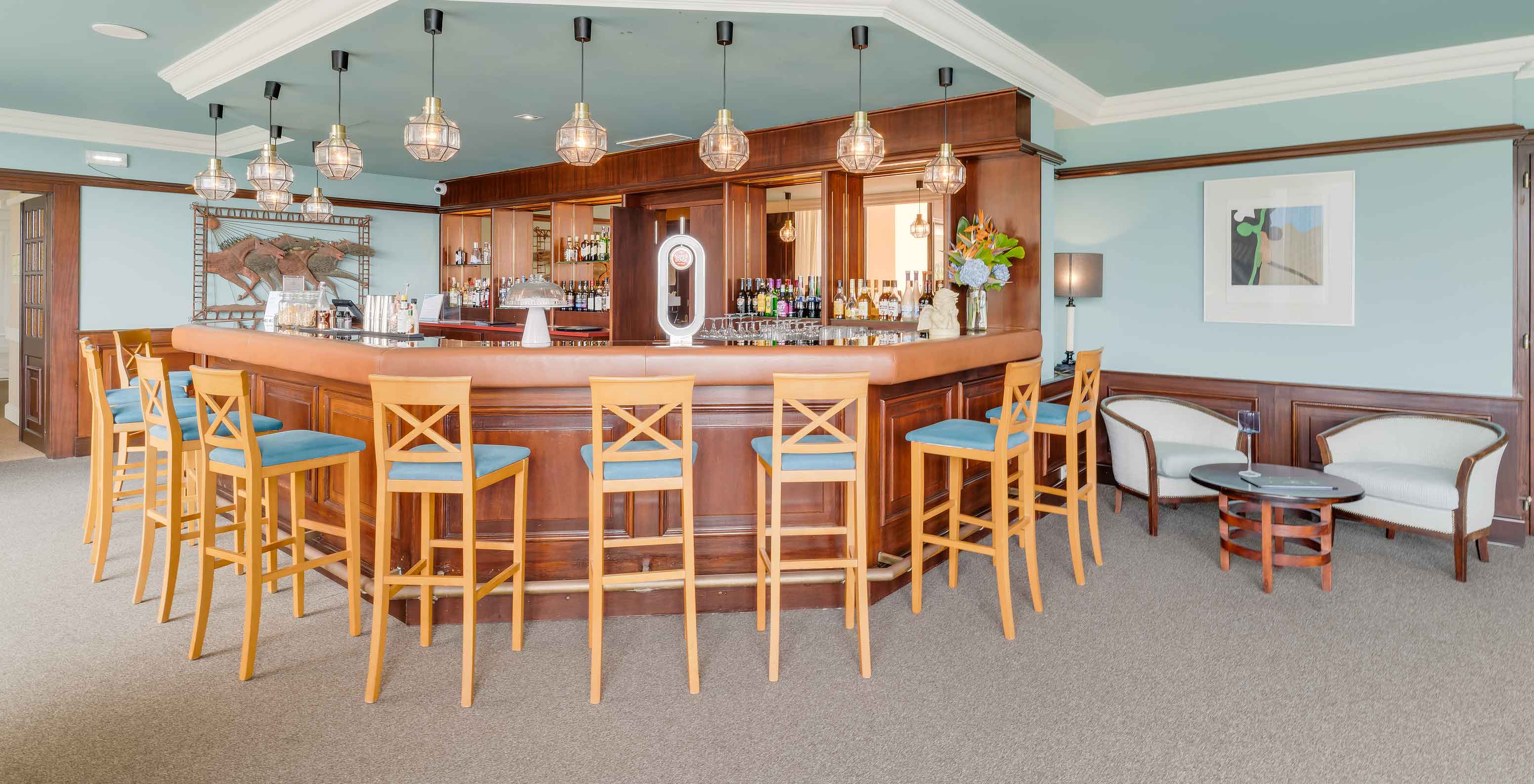 Bar im Pestana Bahia Praia mit hohen Stühlen, Holztresen und moderner Beleuchtung mit hängenden Glühbirnen