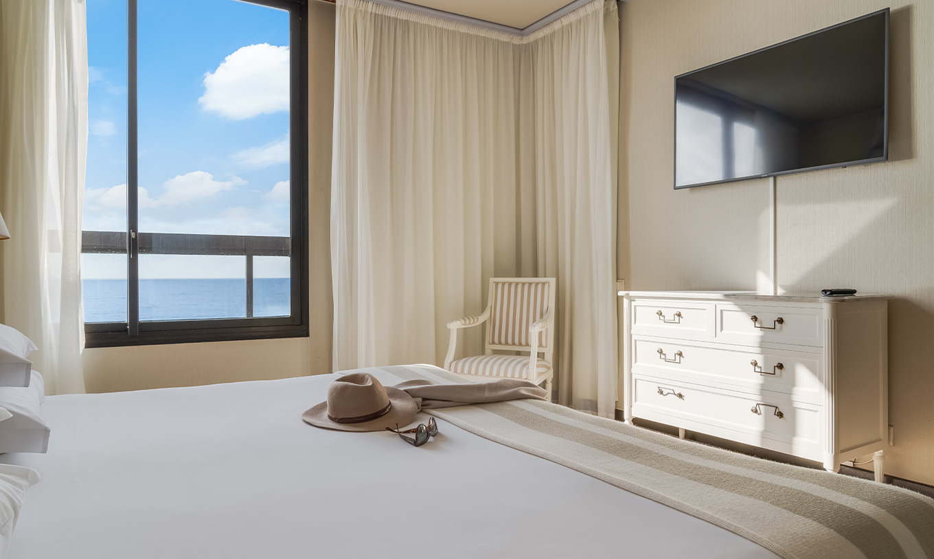 Die Suite im Pestana Bahia Praia hat ein Doppelbett mit Fenster auf der linken Seite und einen Fernseher am Fuß des Bettes