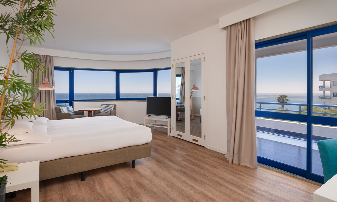 Das Deluxe Superior-Zimmer mit Meerblick im Pestana Cascais hat ein Doppelbett, TV, Spiegel und Blick auf das Meer