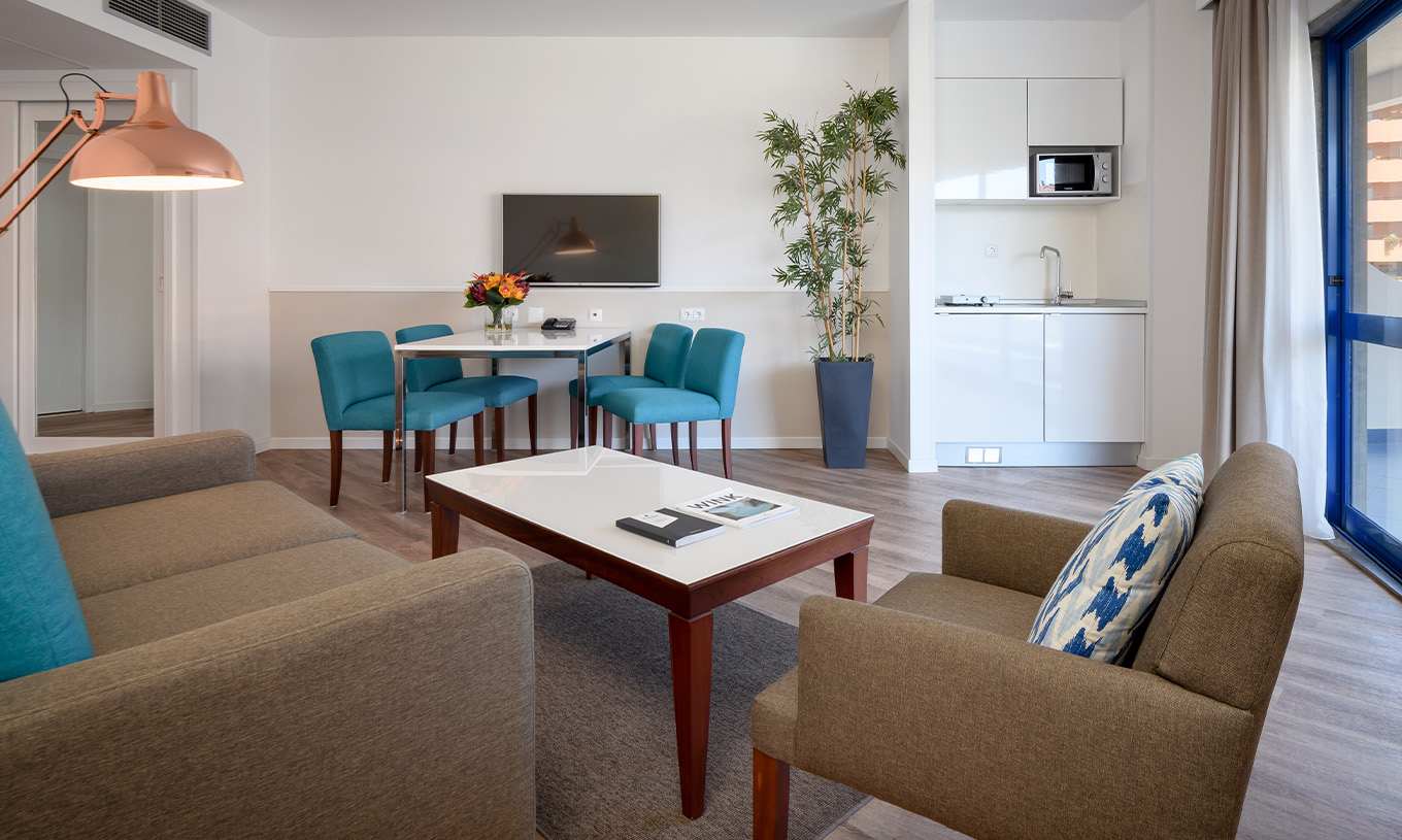 Die Deluxe Suite im Pestana Cascais hat ein Wohnzimmer mit Sofa, Couchtisch, Essbereich und TV