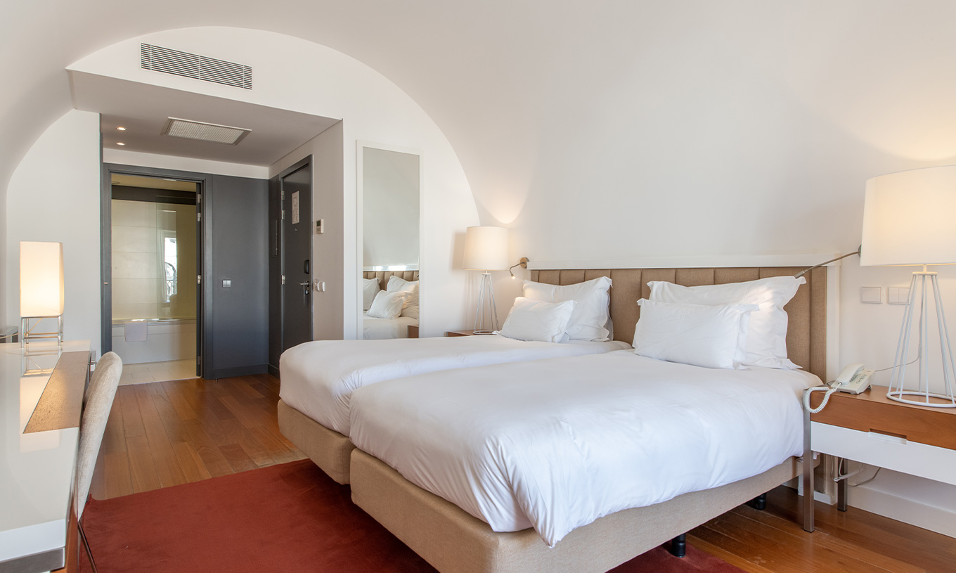 Das Classic Zimmer im Pestana Cidadela Cascais hat zwei Einzelbetten, roten Teppich und einen großen Spiegel