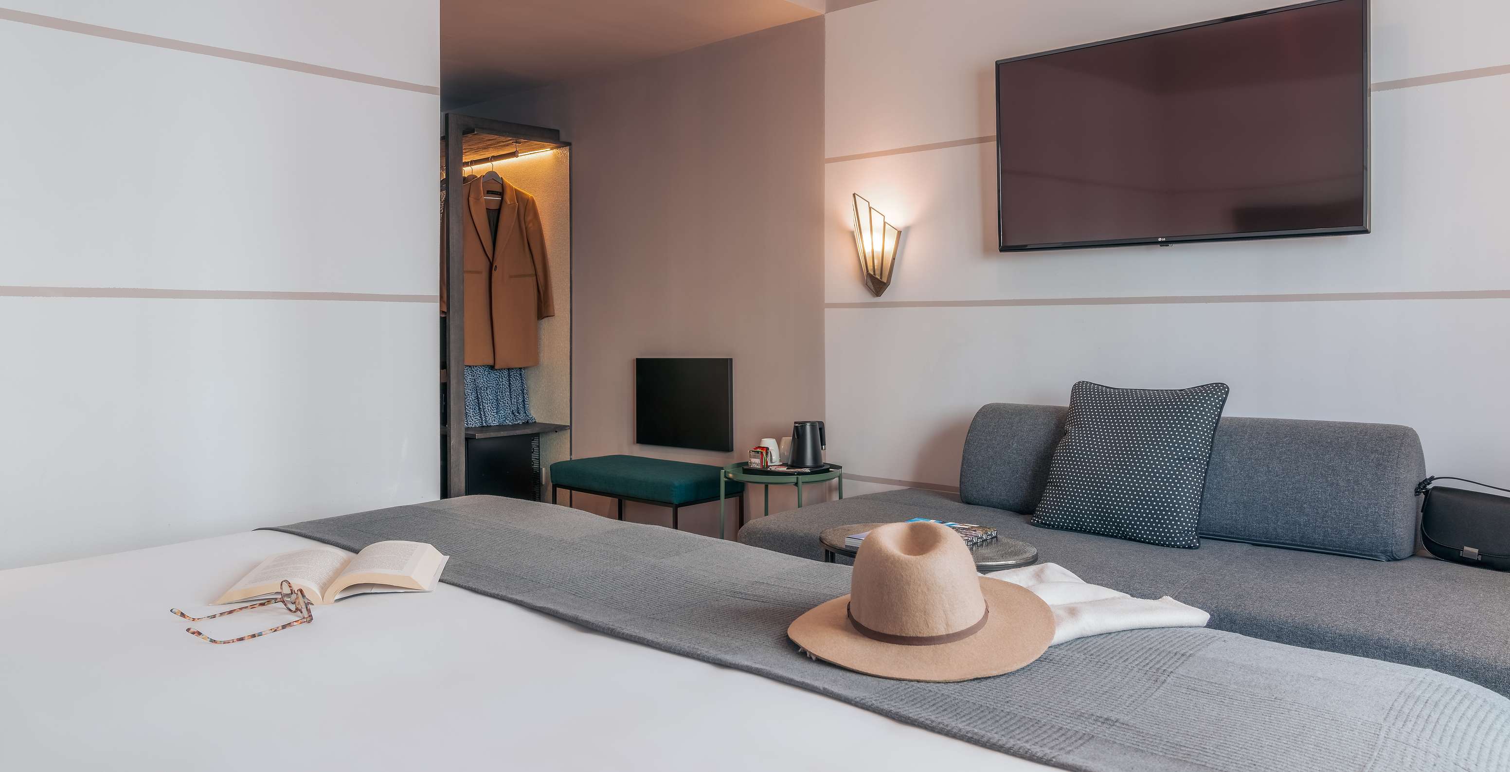 Das Double Classic im Pestana Lisboa Vintage hat Doppelbett mit grauer Decke, graues Sofa und Fernseher