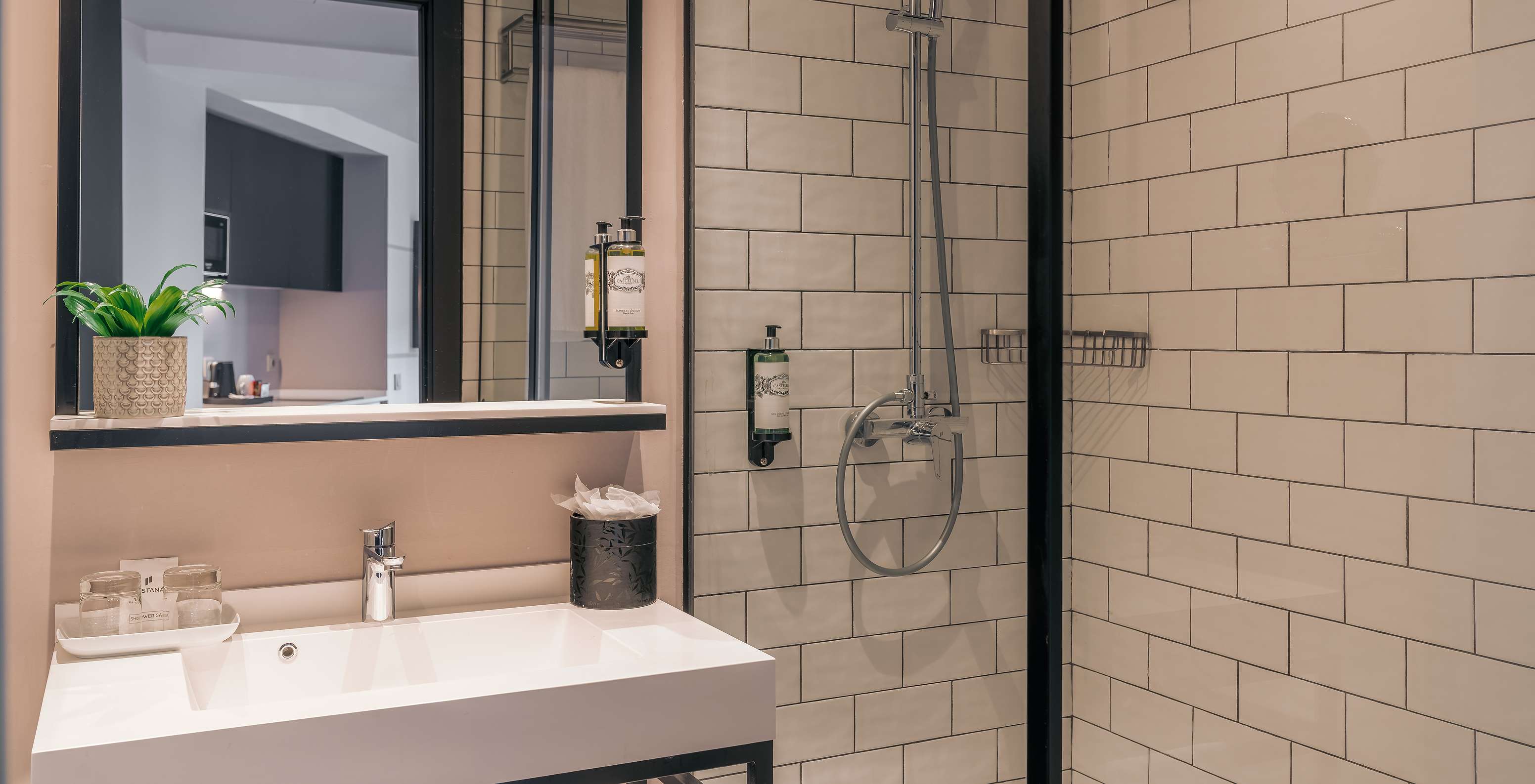 Das Double Deluxe Studio im Pestana Lisboa Vintage hat Dusche mit Glastüren, schwarzen Akzenten und Waschbecken