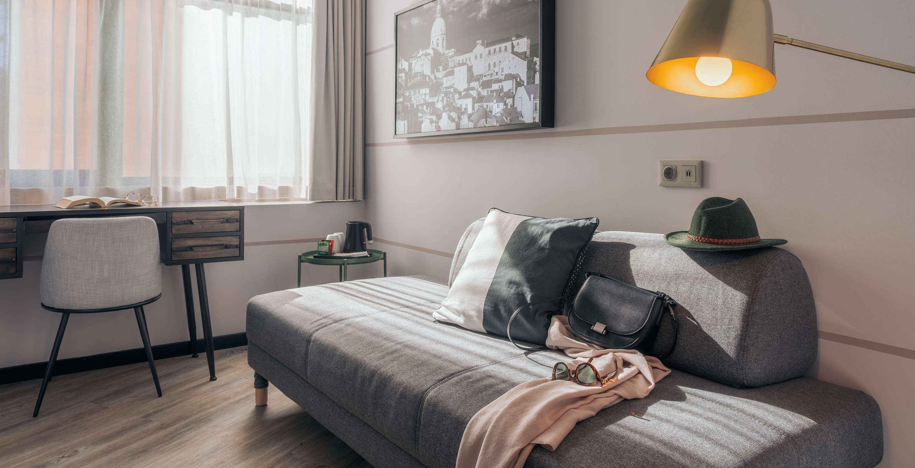 Das Double Superior im Pestana Lisboa Vintage hat graues Sofa, Schreibtisch mit Stuhl, Tisch und Bild