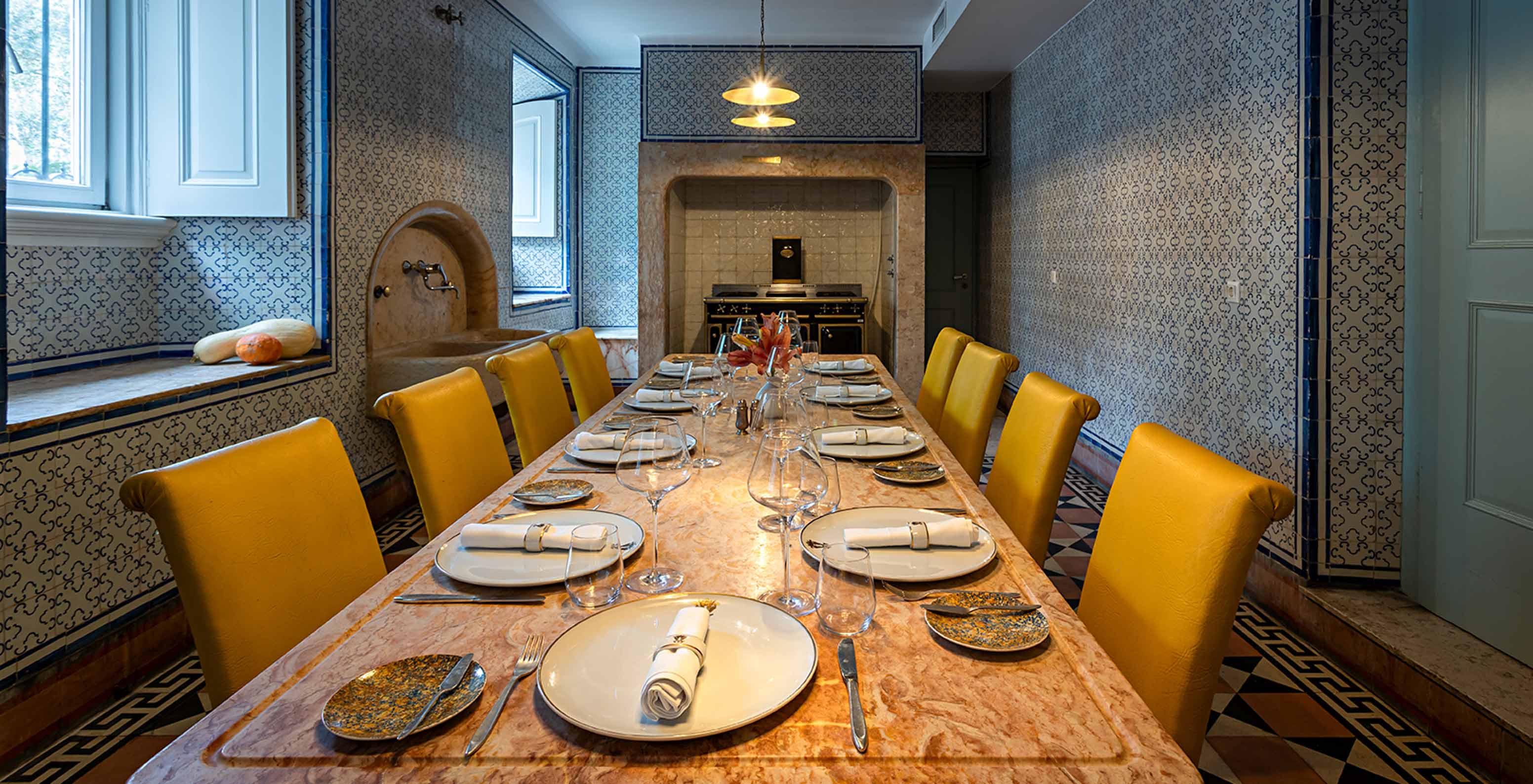 Das Pestana Palace Lisboa hat eine alte Küche für private Veranstaltungen mit einem Steintisch und gelben Stühlen