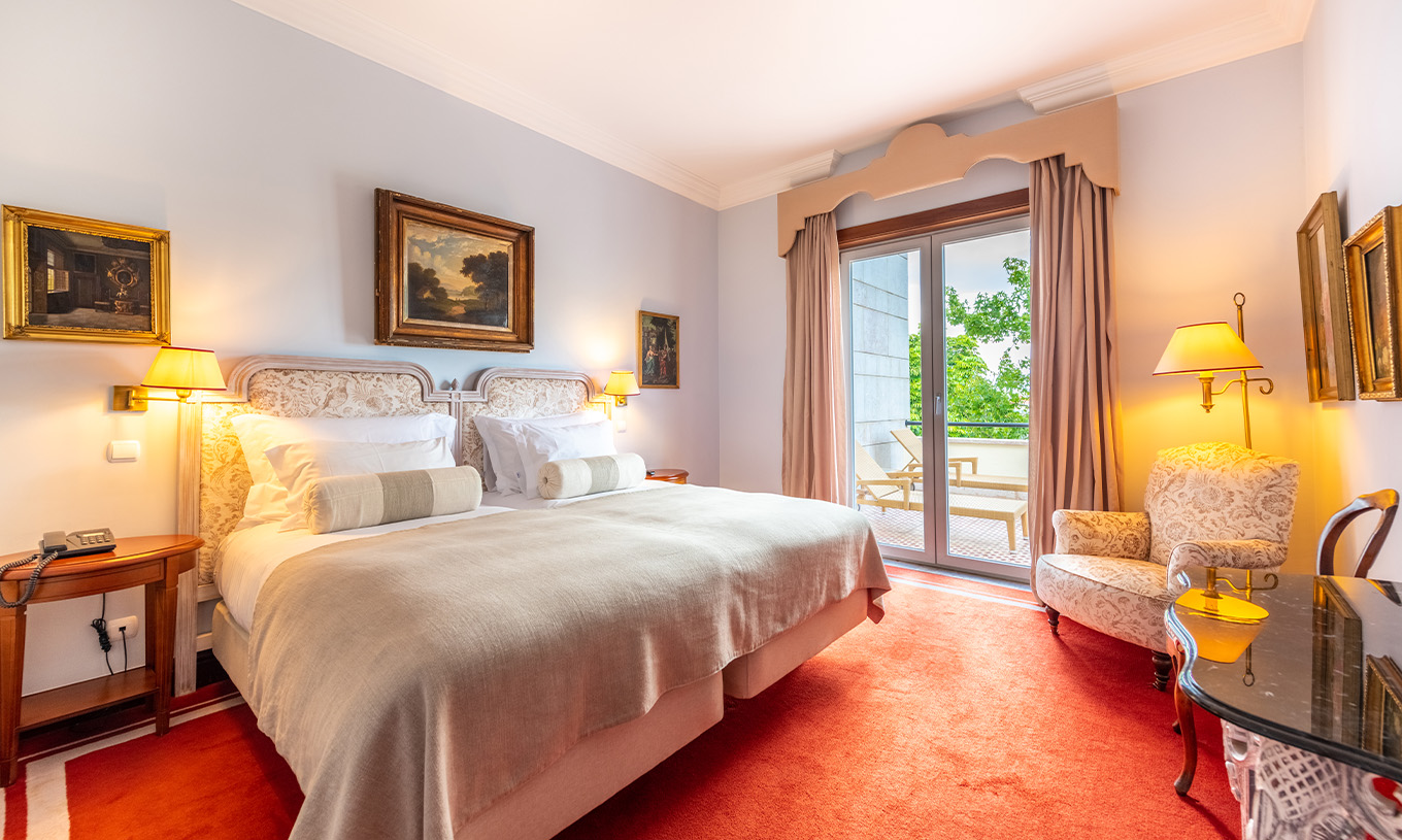 Die Collection Suite im Pestana Palace Lisboa hat ein Doppelbett, Sessel und ein Fenster mit Gartenblick