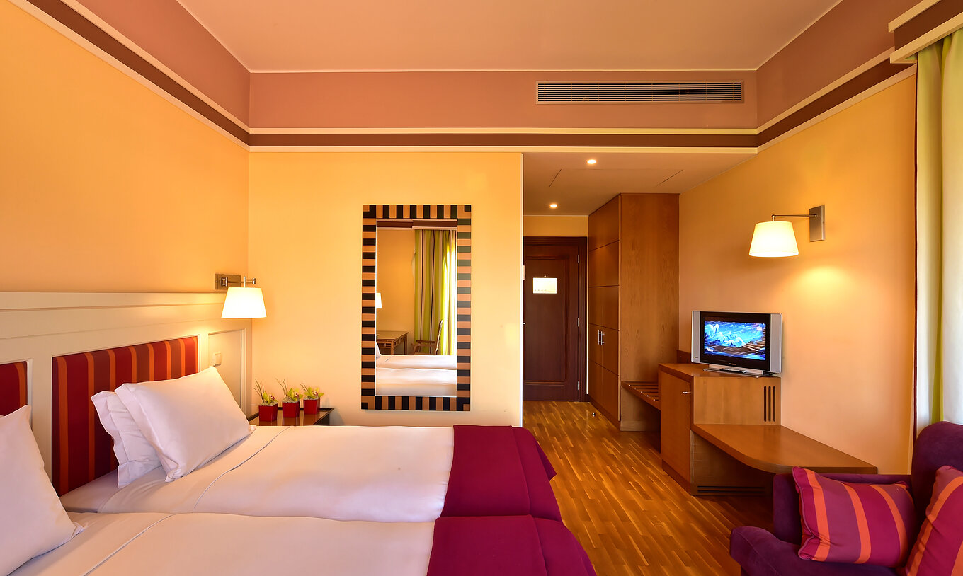 Das Klassische Doppelzimmer mit Gartenblick hat zwei Betten, einen Spiegel und ein Sofa