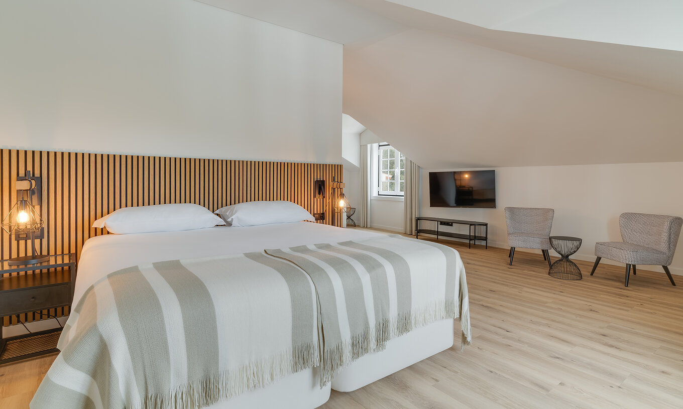 Die Suite im Clubhaus Pestana Sintra Golf hat ein Doppelbett mit Holz-Kopfteil und zwei Stühle