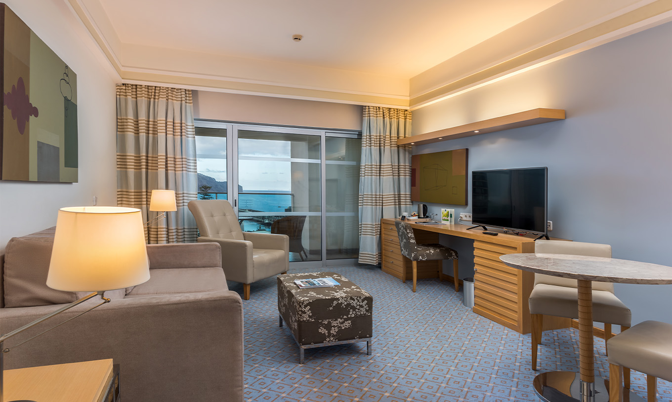 Das Klassische Doppelzimmer mit Meerblick im Pestana Carlton Madeira hat einen Wohnbereich mit Sofa und Fernseher und Balkon