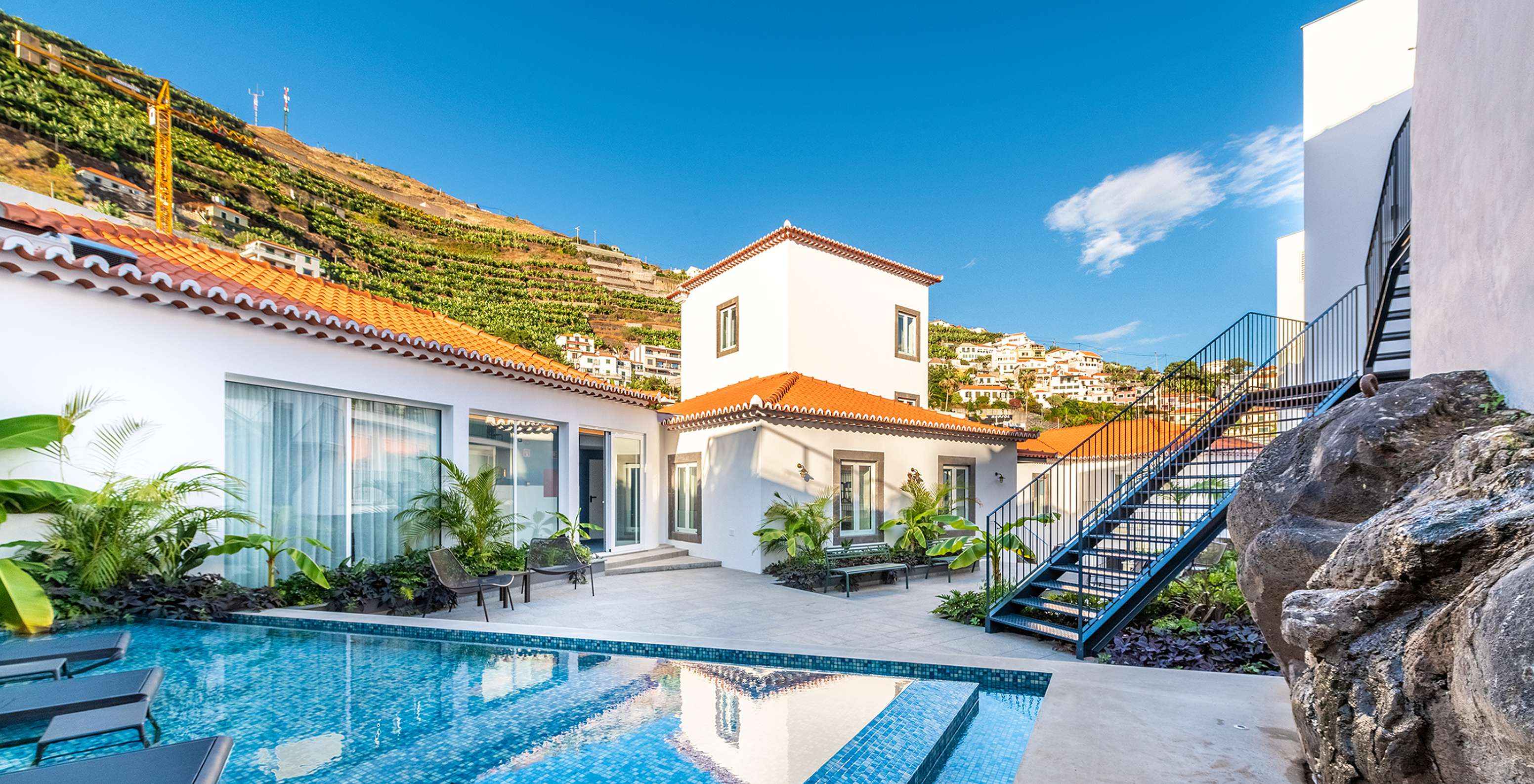 Schwimmbad des Hotels in Câmara de Lobos, Madeira, mit Liegen im Wasser, Pflanzen und Bänken