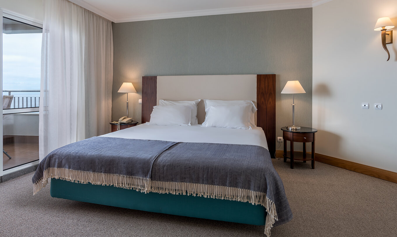 Das Twin Superior Zimmer mit Meerblick im Pestana Grand hat Doppelbett mit Nachttisch und Lampen
