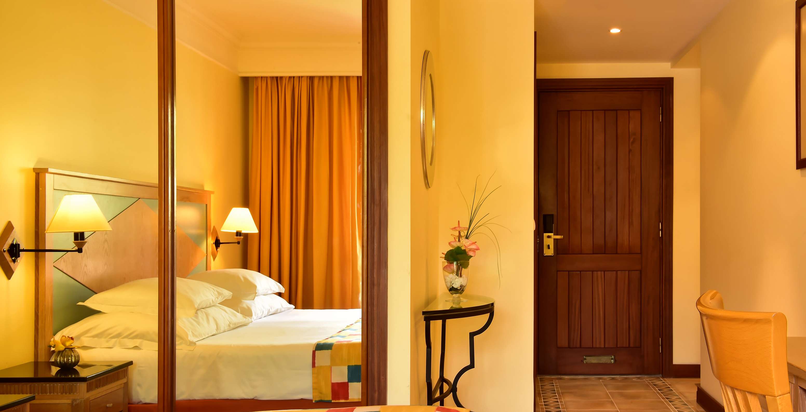 Das Superior im Pestana Miramar hat ein Doppelbett mit kariertem Überwurf und einen Spiegel-Schrank.