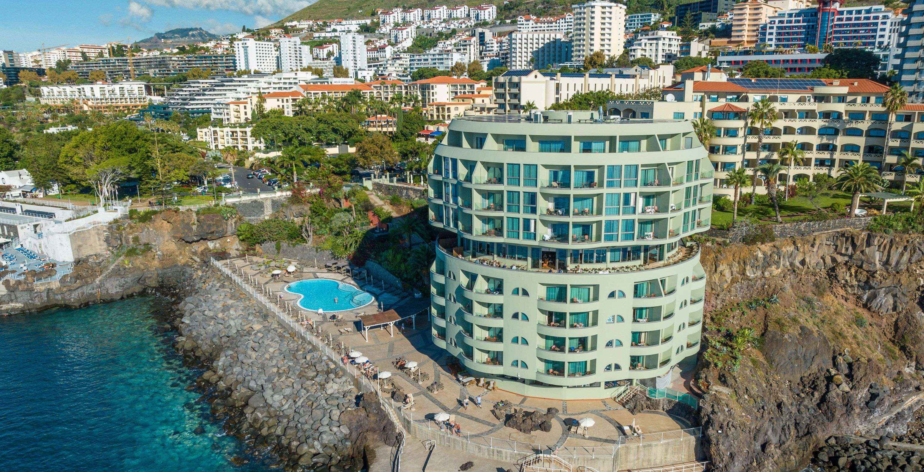 Blick auf das Pestana Vila Lido Madeira, ein Gebäude mit Außenpool, Liegestühlen und direktem Zugang zum Meer