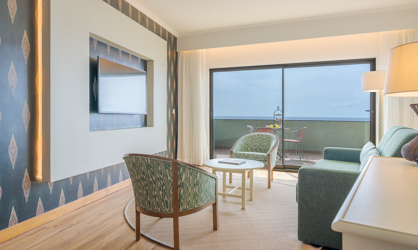 Suite Superior Meerblick Pestana Vila Lido Madeira hat ein Wohnzimmer mit Sofa, Sesseln und Fernseher