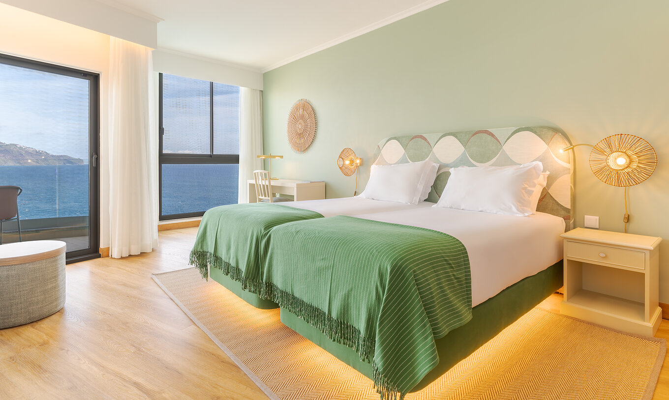 Superior Meerblick Pestana Vila Lido Madeira hat grüne Töne, zwei Betten, einen Schreibtisch mit Stuhl und einen Balkon