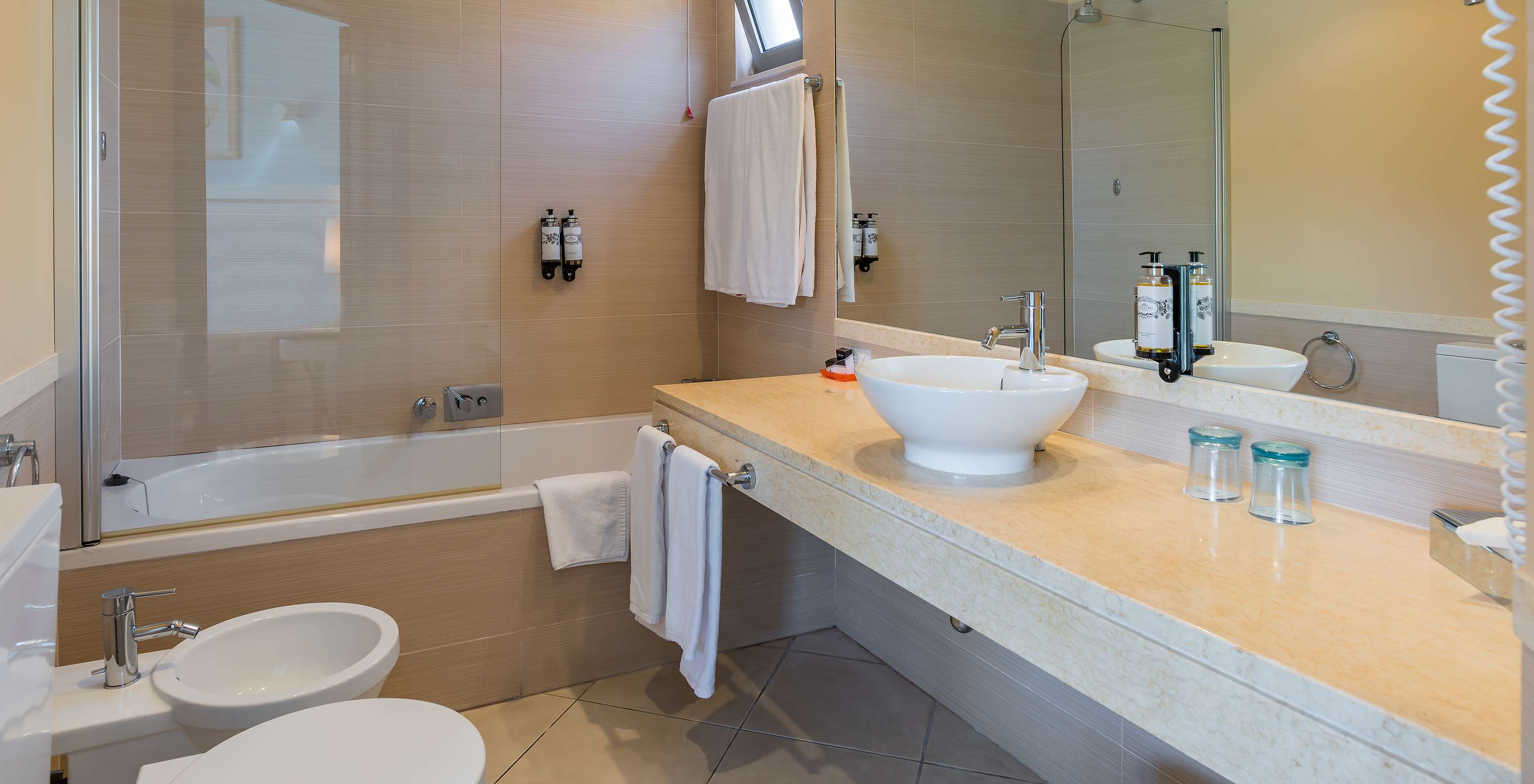 Das Apartment Suite T1 hat ein Bad mit Bidet, Waschbecken, Spiegel und Badewanne 